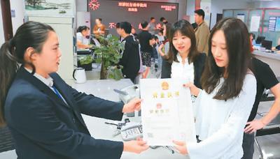 河北省承德市網(wǎng)絡(luò)代購(gòu)經(jīng)營(yíng)者陳晨(右)從工作人員手中接過(guò)帶有統(tǒng)一社會(huì)信用代碼的營(yíng)業(yè)執(zhí)照。 劉環(huán)宇攝(人民圖片)