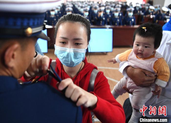 新消防員楊振的妻子彭莉與女兒現(xiàn)場見證丈夫加入“火焰藍(lán)”的神圣時(shí)刻?！⒅铱?攝